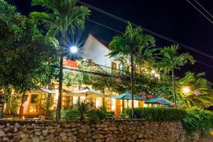 a hotel at night with palm trees and umbrellas at Phong Nha Farmstay in Phong Nha