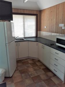 a kitchen with white cabinets and a white refrigerator at Broome Vacation Village in Broome