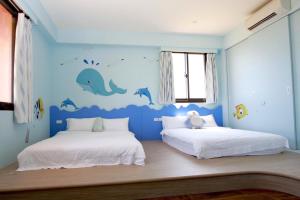 冬山鄉的住宿－桔的堡親子民宿，蓝色客房的两张床,墙上有海豚