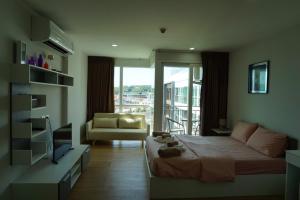 a bedroom with a bed and a couch and a window at Ozone Condotel by Thawinan in Kata Beach
