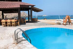 a swimming pool next to a beach with a table and chairs at Hotel Puerto Inka in Chala
