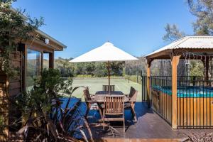 a patio with a table and an umbrella and a pool at The Heyfield Hideaway: Tennis & Spa in Rye