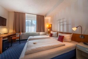 a hotel room with two beds and a desk at Parkhotel Obertshausen in Obertshausen