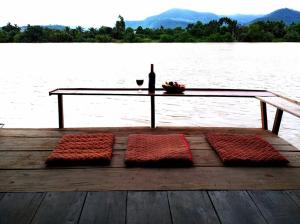 a wooden dock with a table and a bottle of wine at Eden Eco Village in Kampot