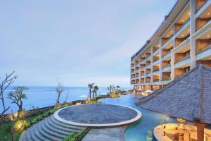 a hotel with a swimming pool next to the ocean at Ulu Segara Luxury Suites & Villas in Nusa Dua