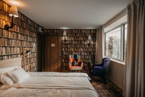 a bedroom with a bed and some chairs and books at Aquapark Design Rooms in Szeged