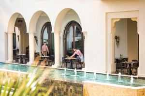 a man sitting at a table next to a swimming pool at Four Seasons Hotel Tunis in Gammarth