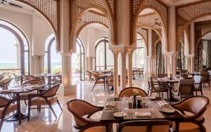 a dining room with tables and chairs and windows at Four Seasons Hotel Tunis in Gammarth