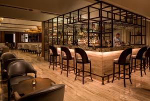 a bar with black chairs and a man standing behind it at Four Seasons Hotel Tunis in Gammarth