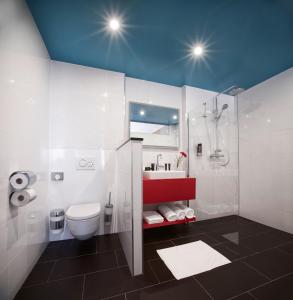 
a bathroom with a toilet, sink, and shower stall at Trans World Hotel Donauwelle in Linz
