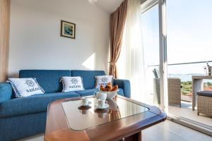 een woonkamer met een blauwe bank en een glazen tafel bij Croatica Suites Podsolarsko in Šibenik