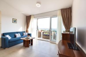 een woonkamer met een blauwe bank en een tafel bij Croatica Suites Podsolarsko in Šibenik