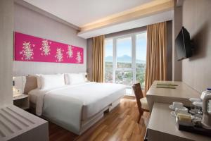 a bedroom with a large white bed and a desk at Hotel Santika Banyuwangi in Banyuwangi