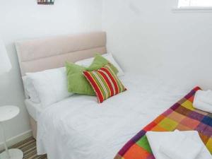 Una cama blanca con almohadas coloridas. en Sea Warrior Cottage en Kilkee