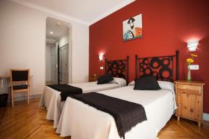 2 Betten in einem Zimmer mit roten Wänden in der Unterkunft Hostal Aresol in Madrid