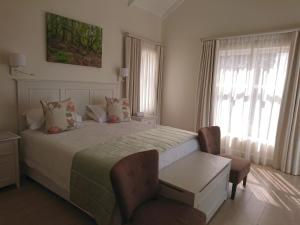 a bedroom with a bed and a chair and windows at Westhill Luxury Guest House in Knysna