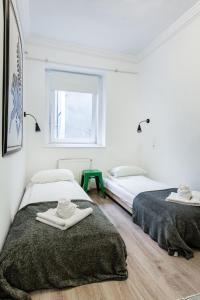 two beds in a white room with towels on them at NY7 Apartment in downtown in Budapest