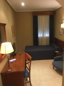 a living room with a bed and a table and a desk at Hotel Manolo Mayo in Los Palacios y Villafranca