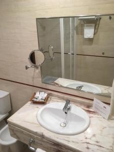 a bathroom with a sink and a mirror and a toilet at Hotel Manolo Mayo in Los Palacios y Villafranca