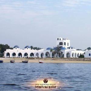 un grupo de edificios blancos a orillas de un cuerpo de agua en New Panorama Resort, en El Fayum