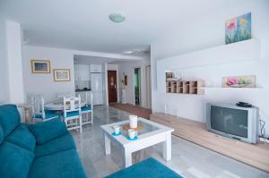 sala de estar con sofá azul y TV en Luminoso y fresco apartamento en 2ª línea de playa, en Fuengirola