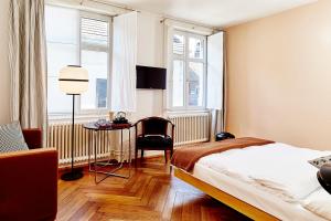 a bedroom with a bed and a chair and windows at Consum Boutique Hotel in Basel