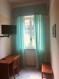 Zimmer mit einem Schreibtisch und einem Fenster mit blauen Vorhängen in der Unterkunft Hotel Elisabetta in Castellammare di Stabia