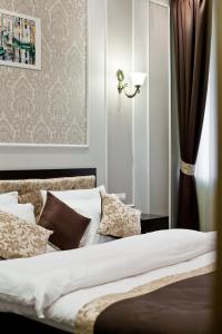 Schlafzimmer mit einem Bett mit weißer Bettwäsche und Kissen in der Unterkunft Boutique Hotel Leningrad in Sankt Petersburg
