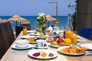 einen Tisch mit Teller mit Speisen am Strand in der Unterkunft Ariadne Beach in Platanias