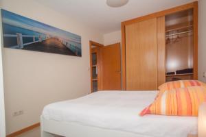 フィニステレにあるBeatiful holiday flat in Finisterre with sea views and next to the "Camino de Santiago"の壁に絵が飾られたベッドのある寝室