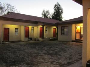 une maison avec des portes rouges et une allée. dans l'établissement Road Stay, à Maseru