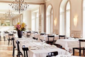 a restaurant with white tables and chairs and a chandelier at Consum Boutique Hotel in Basel