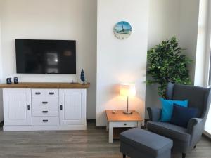 a living room with a television and a chair and a table at Ferienwohnung Oberdeck 2.06 in Glowe