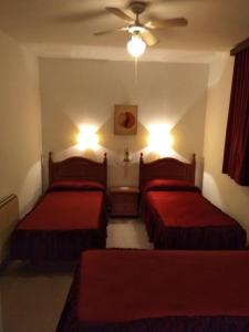 1 Schlafzimmer mit 2 Betten und roter Bettwäsche in der Unterkunft Hostal San Francisco in Campillos