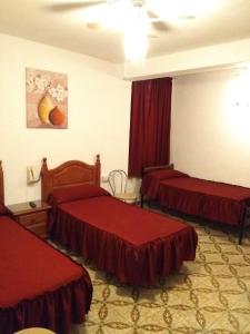 a hotel room with two beds with red sheets at Hostal San Francisco in Campillos