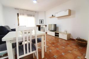 eine Küche und ein Wohnzimmer mit einem Tisch und einem TV in der Unterkunft Global Properties, El Coquetón - Bonito y tranquilo apartamento en Canet playa in Canet d'en Berenguer