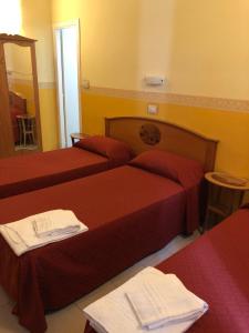 una camera d'albergo con due letti e uno specchio di Hotel Cherubini a Roma