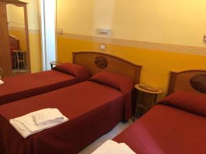 ein Hotelzimmer mit 3 Betten und einem Spiegel in der Unterkunft Hotel Cherubini in Rom