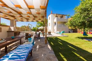 patio ze stołami i krzesłami pod dużym parasolem w obiekcie Aestas Residence, the ultimate summer retreat, By ThinkVilla w mieście Prínos