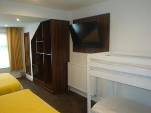 a hotel room with a bed and a flat screen tv at The Sandhurst Hotel in Blackpool