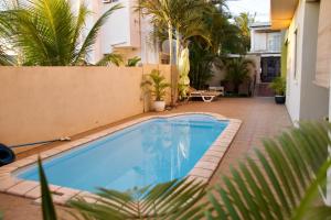 a swimming pool in a courtyard with palm trees at Zanana Penthouse in Flic-en-Flac