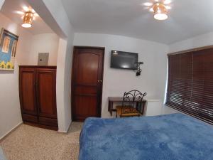 a bedroom with a bed and a tv on the wall at Hotel Maison Gautreaux in Santo Domingo