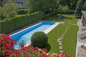 a swimming pool in a yard with red flowers at Parkpension Billroth in Bad Hall