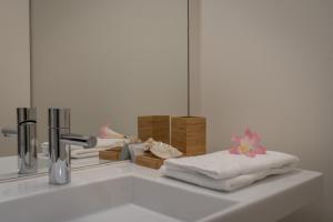 ein weißes Waschbecken mit Handtüchern und einem Spiegel in der Unterkunft AC-Armazéns Cogumbreiro in Ponta Delgada