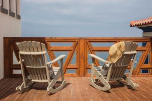 two rocking chairs on a deck with the ocean at Chalet O Amorzinho Sintra Praia in Sintra
