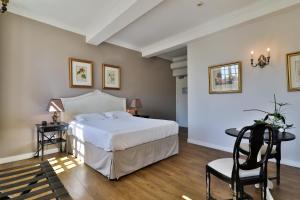 a bedroom with a bed and a desk and a chair at Hotel Du Midi in Visan