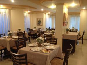 a restaurant with tables and chairs with plates and flowers at Elite Palace Hotel in Prudentópolis