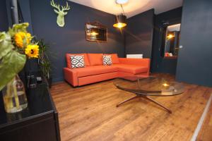 a living room with an orange couch and a glass table at Steine House - Central- by Brighton Holiday Lets in Brighton & Hove
