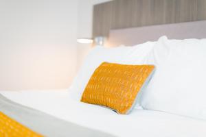 Maldron Hotel Newcastle في نيوكاسل أبون تاين: وسادة صفراء جالسة فوق سرير ابيض