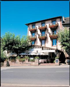 un hôtel avec des tables et des parasols devant un bâtiment dans l'établissement Hôtel des Pyrénées, à Saint-Jean-Pied-de-Port